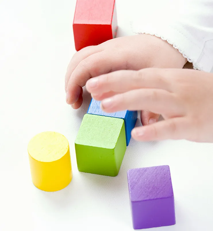 Kind spielt mit bunten Holzbausteinen